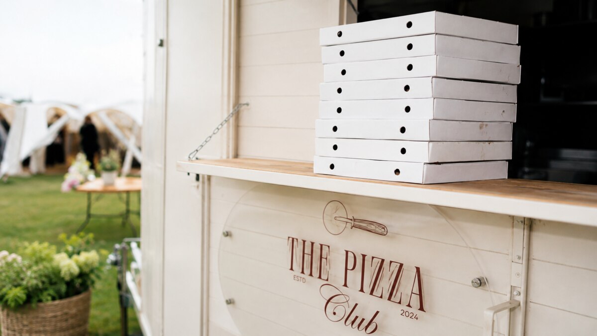 Stacked pizza boxes ready at The Pizza Club trailer during a wedding
